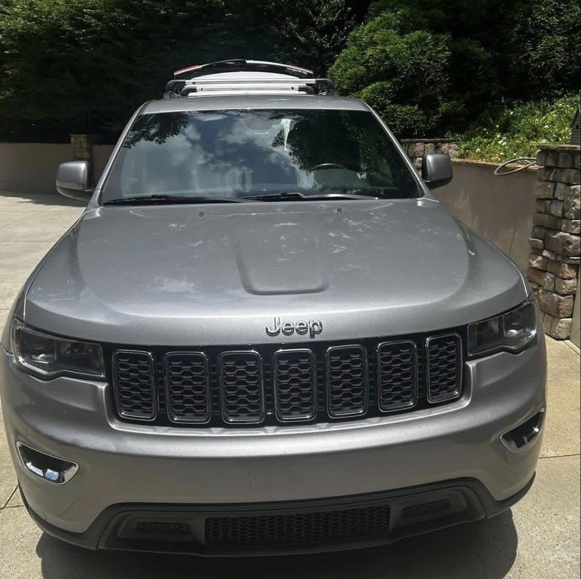 Silver Jeep Grand Cherokee photographed head-on in a driveway after a full detail